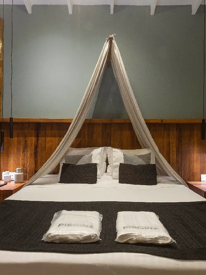 Suíte com cama de mosquiteiro, na luz quente do fim do dia